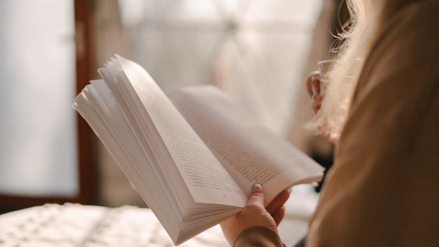 Immagine di presentazione dell'articolo sui classici consigliati per il 2026, con una ragazza di spalle che tiene in mano un libro